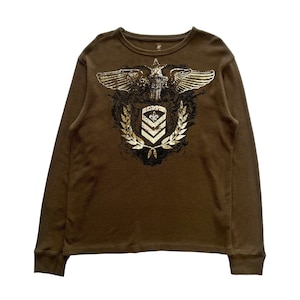 Op de afbeelding: Een bruin longsleeve shirt met een gouden adelaar en schild afbeelding op de voorkant. De afbeelding toont een gestileerde adelaar met gespreide vleugels, een schild met een fleur-de-lis en een lauwerkrans.