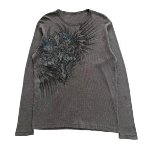 May include: Grey long-sleeved shirt with a graphic print of a blue and black winged cross design.