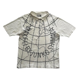 May include: White polo shirt with a black world map design and the text "MAX KEI BY YUNKO SHAMADA" printed on the front. The shirt has short sleeves and a collared neckline.