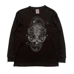Op de afbeelding: Een donkerbruin thermisch shirt met lange mouwen en een ronde hals. Het shirt heeft een groot, sierlijk grafisch ontwerp in grijstinten en wit op de voorkant, inclusief een kroon, de letter "M" en het jaar "2011". Het shirt heeft een geribbelde textuur.