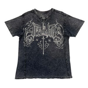 May include: Dark gray short-sleeve t-shirt with a henley neckline and a distressed finish. The shirt features a white graphic design with the word "Affliction" in a stylized font, along with a sword and decorative flourishes.