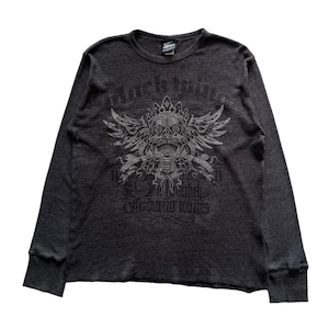 Op de afbeelding: Een donkergrijs longsleeve shirt met een schedelprint en de tekst "Black Wings" gedrukt op de voorkant. De schedel is omringd door vleugels en heeft een kroon op zijn hoofd.