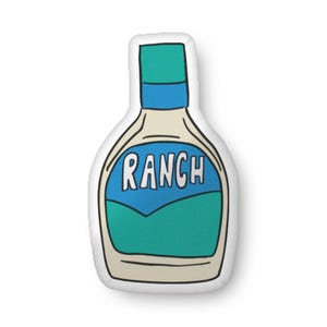 May include: A white pillow shaped like a bottle of ranch dressing. The bottle has a blue label with the word "RANCH" in white letters.