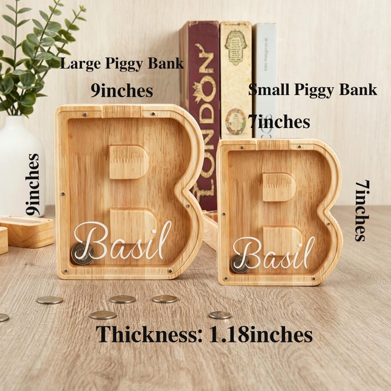 Puede incluir: Dos huchas de madera con forma de letra B y frente de acr&iacute;lico transparente, cada una con el nombre Basil en letra blanca. La hucha grande mide 22,86 cm de alto y la peque&ntilde;a 17,78 cm. Ambas tienen un grosor de 3 cm.