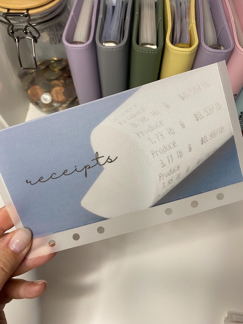 May include: A clear plastic receipt holder with a blue background and the word "receipts" written in cursive. The holder has six holes along the bottom edge and is designed to hold receipts.