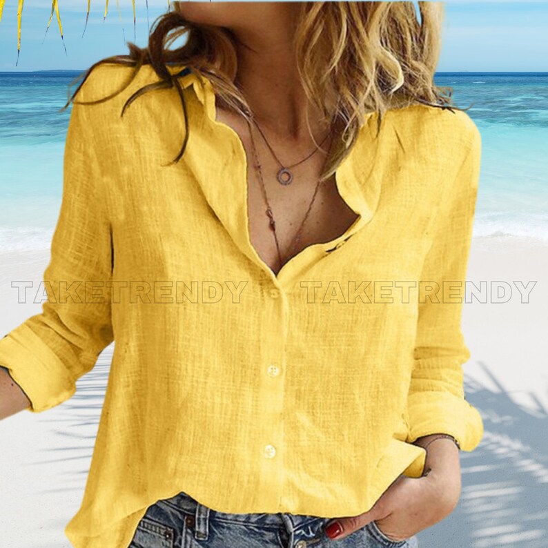 a woman standing on a beach wearing a yellow shirt