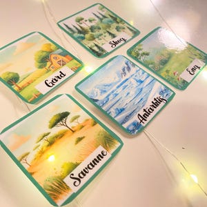 Puede incluir: Cinco tarjetas coloridas con im&aacute;genes de diferentes biomas. Las tarjetas est&aacute;n etiquetadas como "Granja", "Bosque", "Sabana", "Ant&aacute;rtida" y "Pradera".
