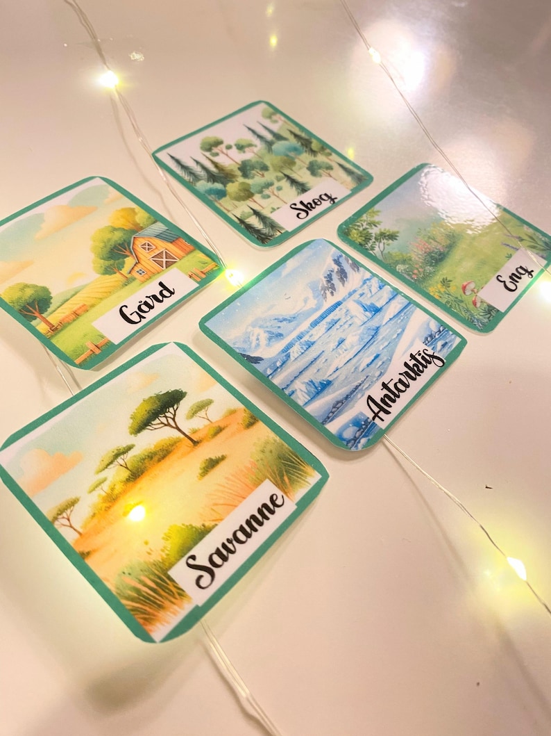 Puede incluir: Cinco tarjetas coloridas con im&aacute;genes de diferentes biomas. Las tarjetas est&aacute;n etiquetadas como "Granja", "Bosque", "Sabana", "Ant&aacute;rtida" y "Pradera".