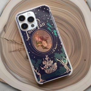 Könnte beinhalten: Eine transparente Handyhülle mit einem marineblauen Hintergrund, auf dem eine Vintage-Illustration von Peter Pan und den verlorenen Jungen zu sehen ist. Die Hülle hat ein glitzerndes Design und der Text "Peter Pan" und "J.M. Barrie" ist auf der Hülle aufgedruckt.