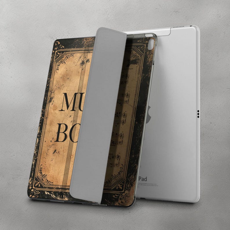 May include: A black and gold iPad case with a vintage book design. The case has the words "Music Book" printed on the front. The case is closed and the iPad is not visible.