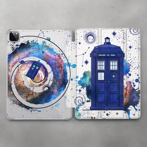 Puede incluir: Una funda blanca para iPad con un diseño de acuarela azul y blanco de una TARDIS, una galaxia en espiral y estrellas. El texto "POLICE BOX" está en la TARDIS.