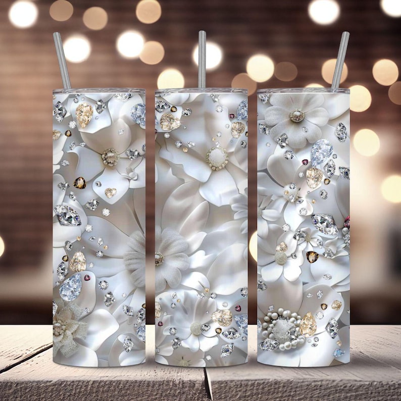 Pu&ograve; includere: Tre bicchieri in acciaio inossidabile con un design floreale bianco e dettagli di glitter argentati. I bicchieri hanno uno sfondo bianco con un motivo di fiori bianchi e glitter argentati.