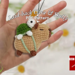 Puede incluir: Un patrón de crochet para un amigurumi de capibara y tortuga. El patrón está disponible para descargar en PDF. La imagen muestra un capibara tejido a crochet con una tortuga en su espalda. El capibara es marrón y la tortuga es verde.