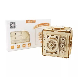May include: A 3D wooden puzzle of a safe with a working dial and gears. The puzzle is made of natural wood and comes with instructions. The box shows a QR code and the text "Hedin craft Building the dream".