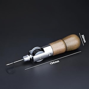 Puede incluir: Una lezna de costura de cuero con mango de madera y cuerpo de metal plateado. La lezna mide 13,4 cm de largo y 3,5 cm de ancho. Tiene una aguja y una bobina de hilo negro. La herramienta est&aacute; dise&ntilde;ada para coser cuero y otros materiales.