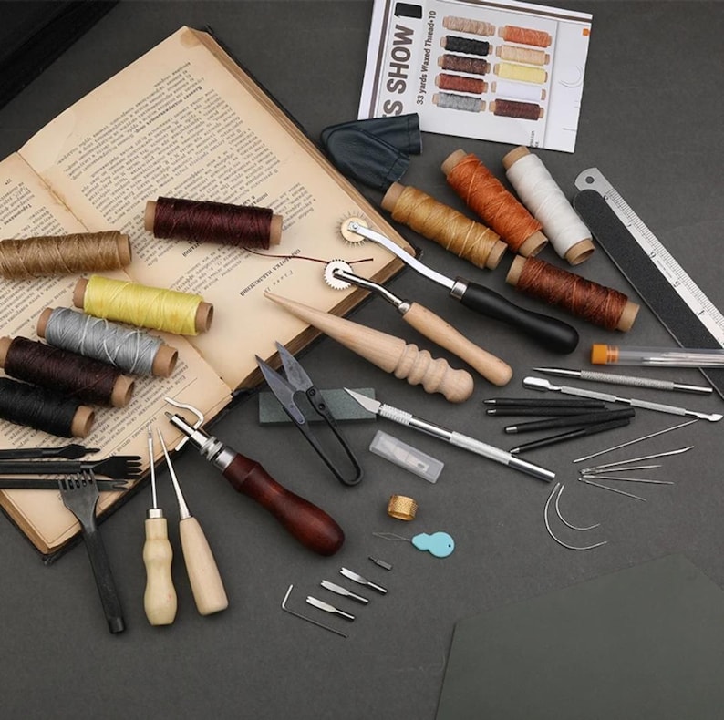 May include: A leather craft tool kit with a variety of tools, including needles, awls, a stitching pony, a stitching groover, a leather punch, and a ruler. The kit also includes several spools of waxed thread in different colors.