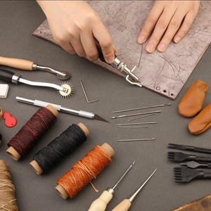 May include: A set of leather crafting tools including needles, awls, thread, a stitching pony, and a leather hole punch.