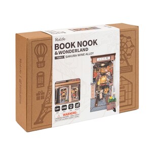 May include: A Rolife Book Nook & Wonderland kit, model TGB11, featuring a Sakura Wine Alley scene. The box is brown with illustrations of a hot air balloon, Eiffel Tower, and Ferris wheel. The kit includes 249 pieces and is for ages 14+.