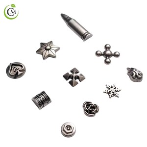 K&ouml;nnte beinhalten: Eine Sammlung silberfarbener Metallverzierungen in verschiedenen Formen, darunter eine Kugel, ein Stern, ein Kreuz und eine Rose. Die dekorativen Elemente sind auf wei&szlig;em Hintergrund angeordnet und zeigen ihre komplizierten Designs und Texturen.