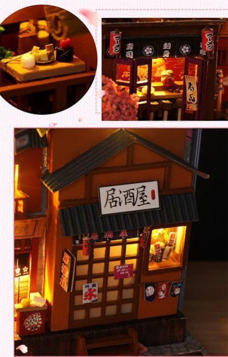 K&ouml;nnte beinhalten: Miniaturmodell eines japanischen Restaurants mit Holzfassade, beleuchteten Fenstern und einem Schild mit der Aufschrift "Izakaya". Das Modell enth&auml;lt kleine Details wie Papierlaternen und Miniatur-Lebensmittel.