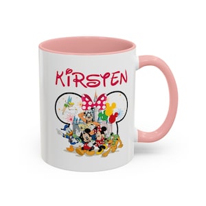 Puede incluir: Taza de cer&aacute;mica blanca con interior y asa rosas. La taza presenta un dise&ntilde;o tem&aacute;tico de Disney con Mickey y Minnie Mouse, el Pato Donald y Goofy. El nombre "Kirsten" est&aacute; impreso en rosa encima de los personajes.