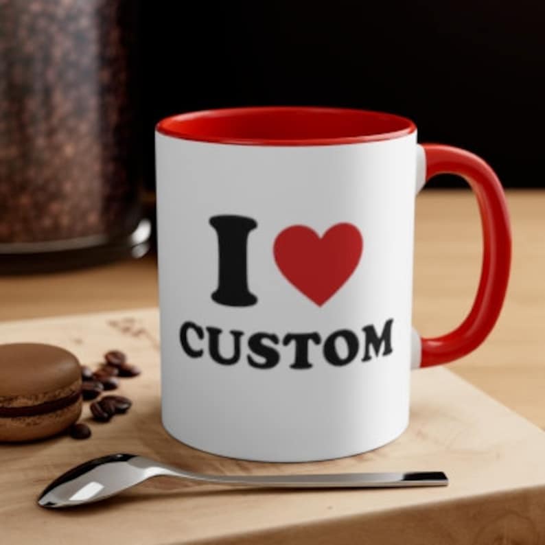 May include: White ceramic coffee mug with a red rim and handle. The mug has a black graphic that says "I love CUSTOM" with a red heart.