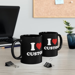 May include: Two black ceramic mugs with white text that reads "I love custom" and a red heart.