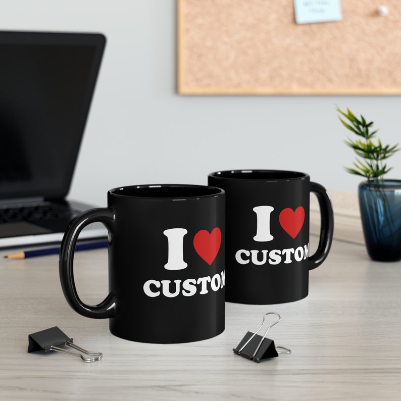 May include: Two black ceramic mugs with white text that reads "I love custom" and a red heart.