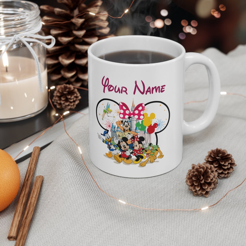 Puede incluir: Taza de cer&aacute;mica blanca con un dise&ntilde;o de Disney. La taza presenta a Mickey y Minnie Mouse, el Pato Donald y Goofy. El texto "Your Name" est&aacute; escrito en cursiva. El dise&ntilde;o est&aacute; sobre un contorno negro de orejas de Mickey Mouse.
