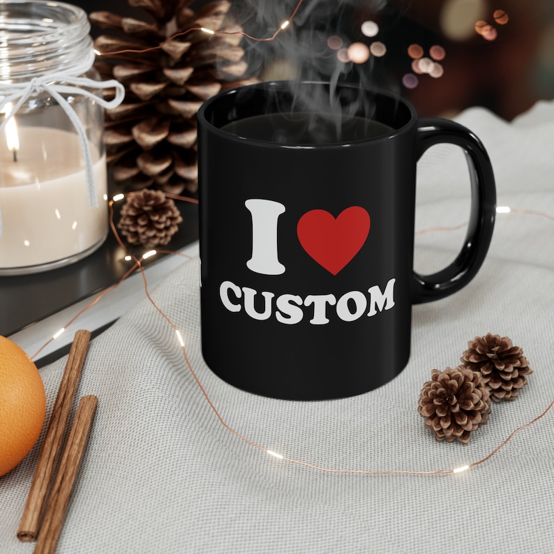 May include: Black coffee mug with white text that reads "I &hearts; CUSTOM". The heart is red.