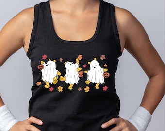 May include: Black tank top featuring a Halloween-themed design. The graphic shows three cartoon ghosts holding jack-o'-lanterns and surrounded by autumn leaves. The ghosts have yellow feet and are wearing white sheets.