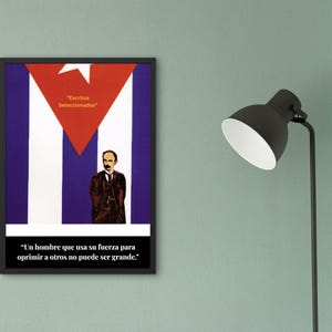 May include: Framed poster featuring the Cuban flag design with a red triangle and white star. The poster includes a portrait of a man and text in Spanish: "Escritos Seleccionados" and a quote. The poster is displayed on a green wall.