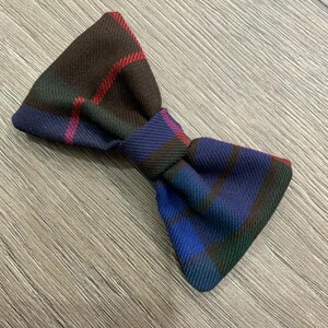 May include: A plaid bow tie in shades of brown, blue, red, and green.