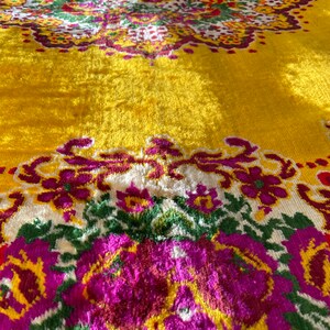 May include: A yellow throw blanket with a floral pattern in shades of pink, green, and white. The blanket has a textured, fuzzy surface.