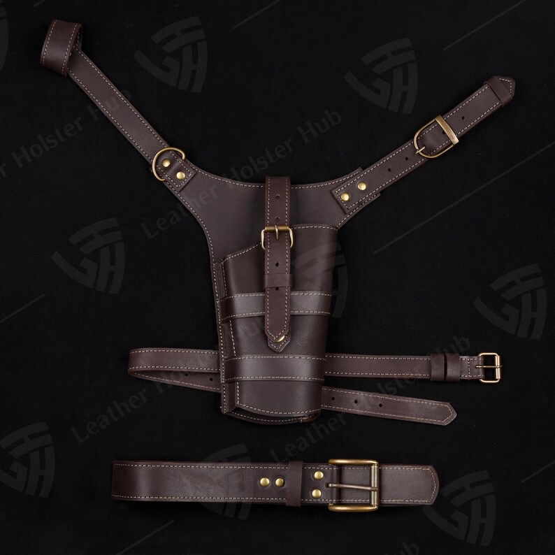May include: A brown leather holster with a belt and shoulder straps. The holster has a stitched design and brass buckles.