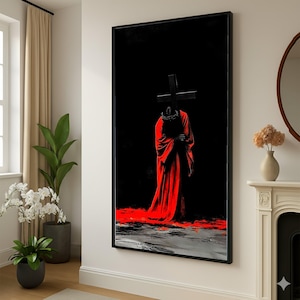 May include: Framed art print featuring a figure in a red robe holding a black cross against a black background. The artwork has a dramatic, artistic style with a splash of red at the bottom, creating a striking visual contrast.