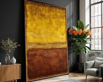 May include: Large abstract painting with a black frame. The artwork features a horizontal division of color, with a golden yellow upper section and a deep brown lower section. The painting is displayed in a modern living room setting.