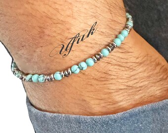 May include: A turquoise and silver beaded bracelet on a person's wrist.