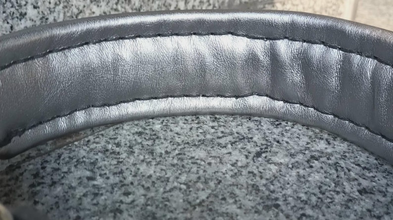 Puede incluir: Primer plano del acolchado de la diadema de unos auriculares de color plateado. La diadema est&aacute; hecha de un material suave y acolchado y tiene una costura cosida.