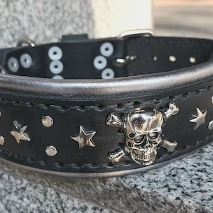 Puede incluir: Collar de perro de cuero negro con detalles plateados, con un dise&ntilde;o de calavera y huesos cruzados y tachuelas en forma de estrella.