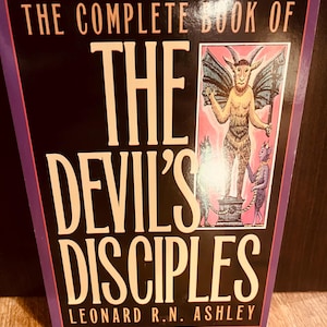 Pu&ograve; includere: Un libro intitolato "THE COMPLETE BOOK OF THE DEVIL'S DISCIPLES" di Leonard R.N. Ashley. La copertina presenta uno sfondo nero con testo bianco e un bordo viola. Un'illustrazione di una figura simile al diavolo &egrave; sul lato destro.