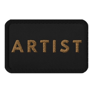 May include: Black fabric patch with a gold embroidered word "ARTIST" on it.