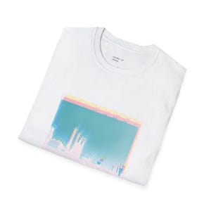 Op de afbeelding: Wit T-shirt met een grafische print van een stadsbeeld met een glitch-effect in roze, blauw en geel. De tekst "SECOND 1 OF DESIGN" is op het T-shirt gedrukt.