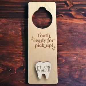 May include: Wooden tooth fairy door with a cutout for a tooth and the text "Tooth, ready for pick up!" with a small tooth cutout with the name "DAWSYN" on it.