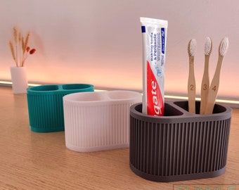 May include: A brown, two-compartment toothbrush holder with three wooden toothbrushes and a tube of Colgate Baking Soda & Peroxide Whitening toothpaste.