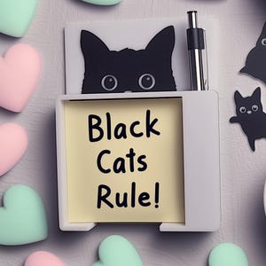 May include: A white desk organizer with a black cat silhouette and the text "Black Cats Rule!" on a yellow sticky note. The image includes pink and mint green heart-shaped decorations and black cat stickers.