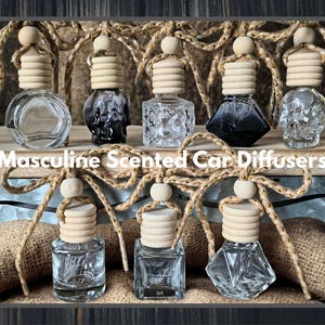May include: An assortment of car air fresheners with wooden tops and decorative rope accents. The glass bottles come in various shapes, including a skull, and are filled with scented oils. The text "Masculine Scented Car Diffusers" is displayed.