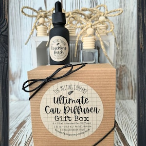 May include: A car diffuser gift box with a black bow. The box has a round label with the text "Ultimate Car Diffuser Gift Box". A black bottle with "Crackling Birch" label and a small clear bottle are also visible.