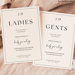 Puede incluir: Dos carteles blancos con texto negro y bordes. Los carteles son para una recepción de boda e indican la ubicación de los baños. El texto en los carteles dice "JD Ladies" y "JD Gents". Los carteles también incluyen el texto "Por favor, sírvete" y "Aquí hay una cesta para ayudarte". Los carteles también incluyen el texto "Ahora date prisa y vuelve antes de que te pierdas la siguiente canción". Los carteles están firmados "Jennifer & David Oct 12 2024".