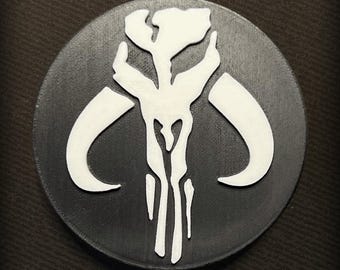 May include: A black and white Mandalorian symbol, a skull with horns, is printed on a round, black coaster.
